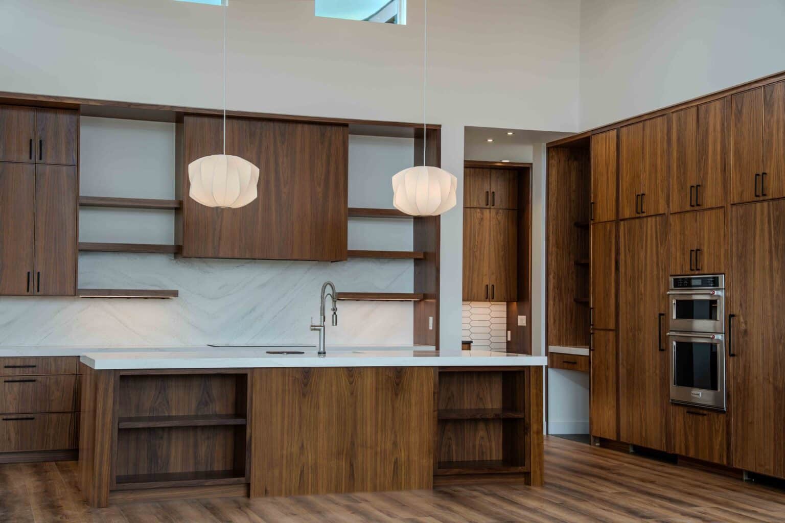 Open plan kitchen with dark wood cabinetry and white stone countertops connecting to adjacent living spaces