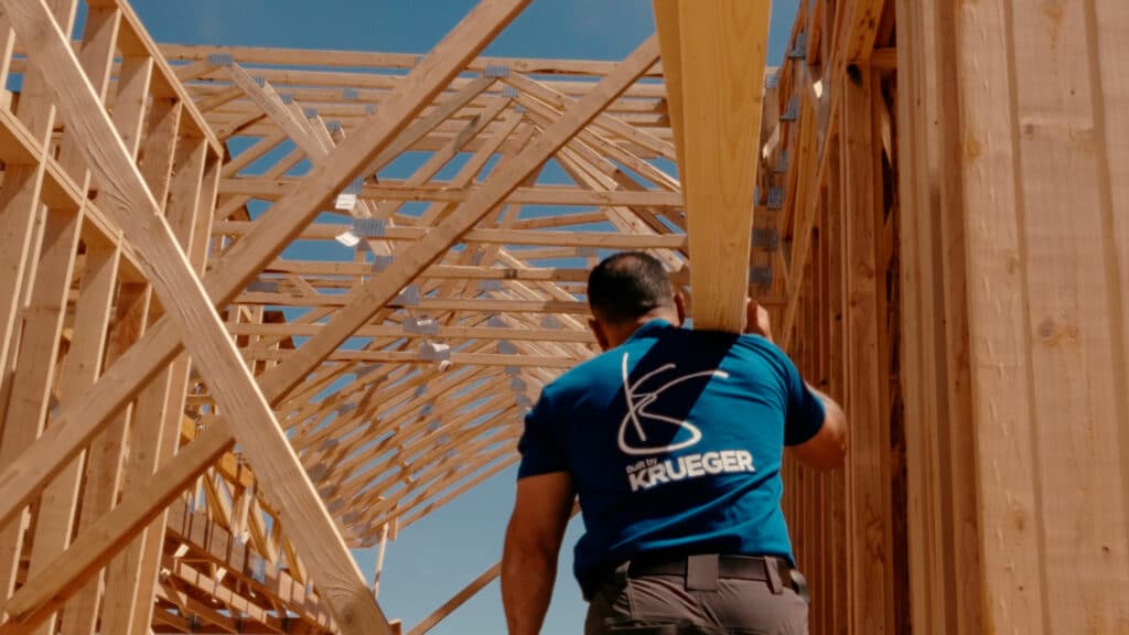 Lead Carpenter Nelson Calderon carrying planks of wood to a house under construction in the Built By Krueger Commercial