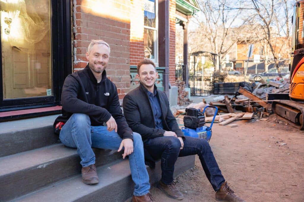 Two men sitting on steps, smiling.